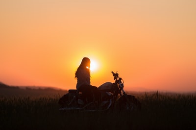 女人骑摩托车巡洋舰在金色的小时
